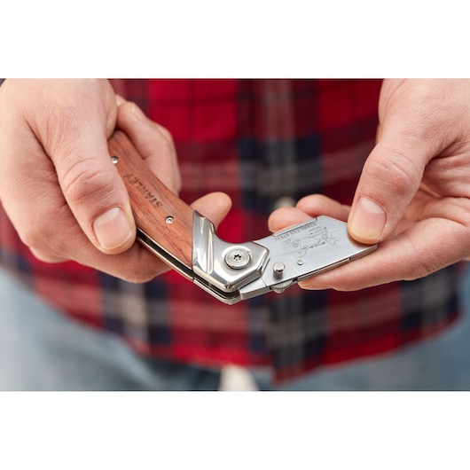 Photo of STANLEY 0-10-073 folding utility knife with wooden handle held in hand.
