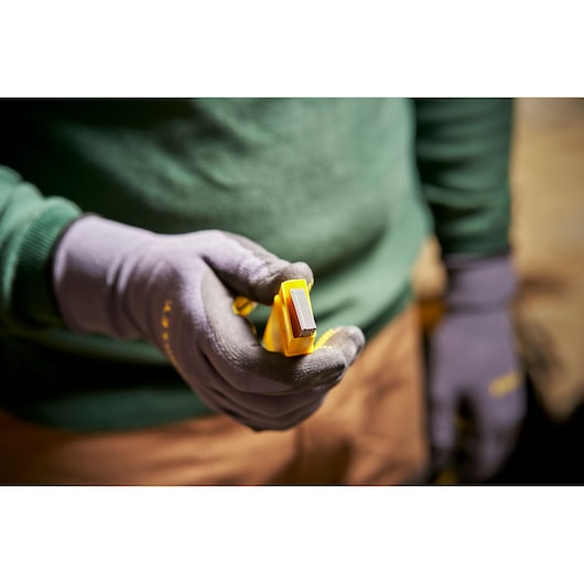 Photo of STANLEY 0-11-325 utility blades pack held in gloved hand, close-up view.