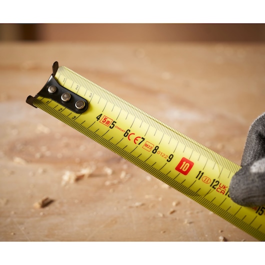 Stanley 0-33-720 yellow tape measure close-up showing metric markings, photography, wood background.