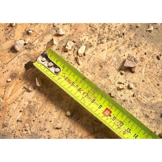 STANLEY 0-33-897 tape measure photography on dusty wood surface with rocks and debris.