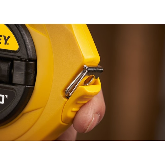 STANLEY 0-34-107 yellow measuring tape with black and red markings, extended across a brown surface.