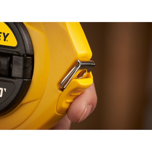 STANLEY 0-34-107 yellow tape measure close-up showing metal hook and hand detail.