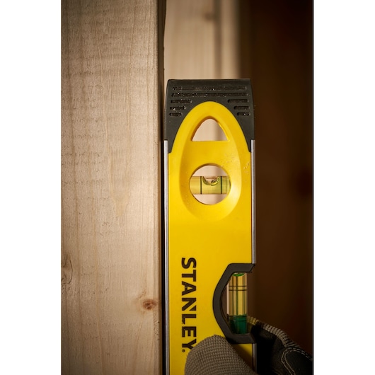 Photo of STANLEY 0-43-511 spirit level held vertically against wood, visible vial and yellow body.