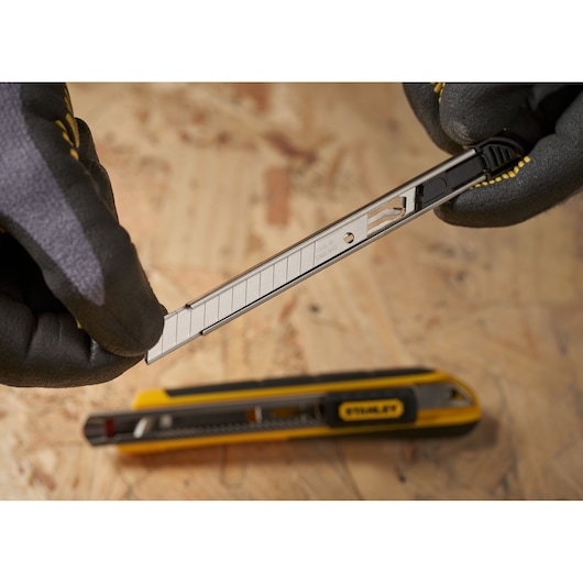 STANLEY 1-11-300 snap-off blade utility knife in use, close-up photography on plywood surface.