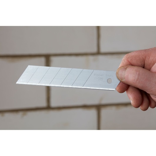 STANLEY 1-11-325 snap-off utility blade held in hand, silver finish, segmented design, photography.