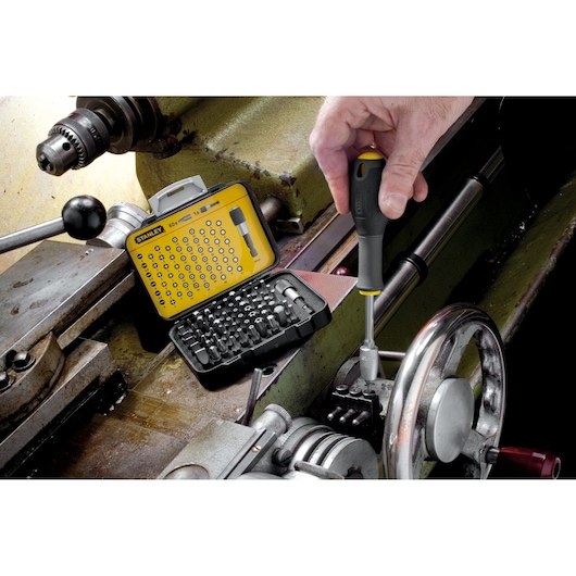 Stanley SKU 1-13-902 screwdriver bit set in yellow case used for machinery repair, close-up photography.