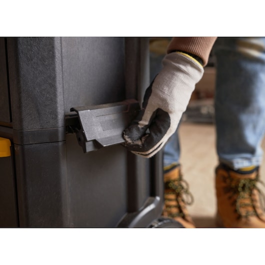 STANLEY 1-79-206 tool storage latch close-up, worker gloved hand operating black latch