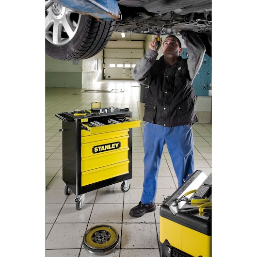 STANLEY 1-94-737 yellow and black tool trolley with open drawer in auto workshop setting.