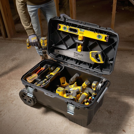 STANLEY 1-94-850 rolling tool chest open, filled with hand tools and power tools on construction site.