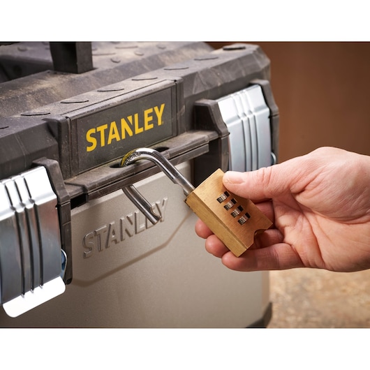 Close-up of STANLEY 1-95-615 toolbox with metal latches, being locked with a brass combination padlock.