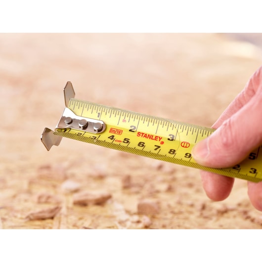 Photo of STANLEY 5-33-886 tape measure extended, with yellow blade and clear markings, held by a hand.