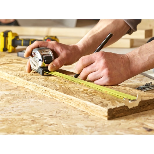 STANLEY 5-33-886 tape measure photo, measuring wood plank, close up in workshop setting.