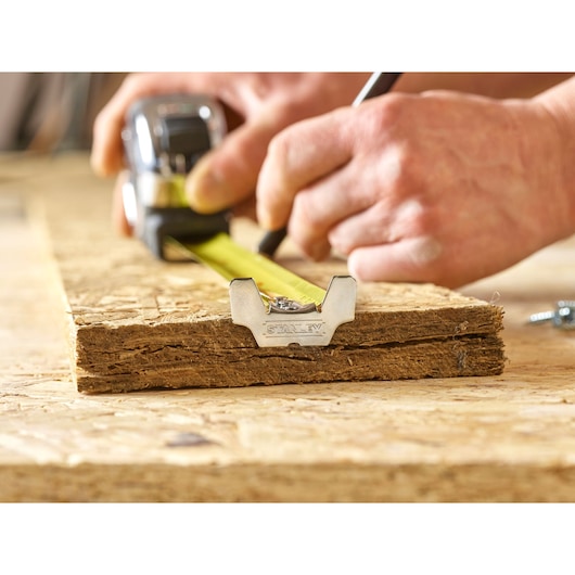 Photo of STANLEY 5-33-886 tape measure in use, measuring wood plank on workbench.