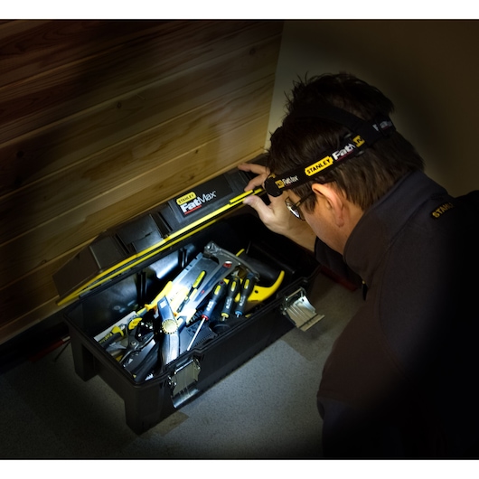 STANLEY FMHT0-70767 photography of person using headlamp to view open toolbox with Stanley tools.