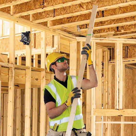 STANLEY FMHT1-77348 laser level mounted on wooden framing, construction site background.