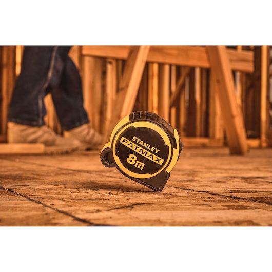 STANLEY FMHT33103-3 tape measure, FATMAX, 8m, black and yellow, on construction site floor.