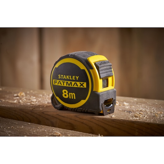 STANLEY FMHT33103 tape measure FATMAX 8m, yellow and black, shown on a wooden surface.