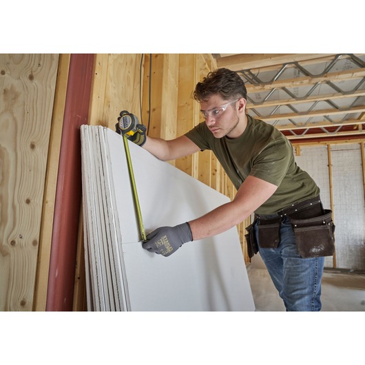 STANLEY FMHT38215-5 tape measure used to measure drywall in construction site.