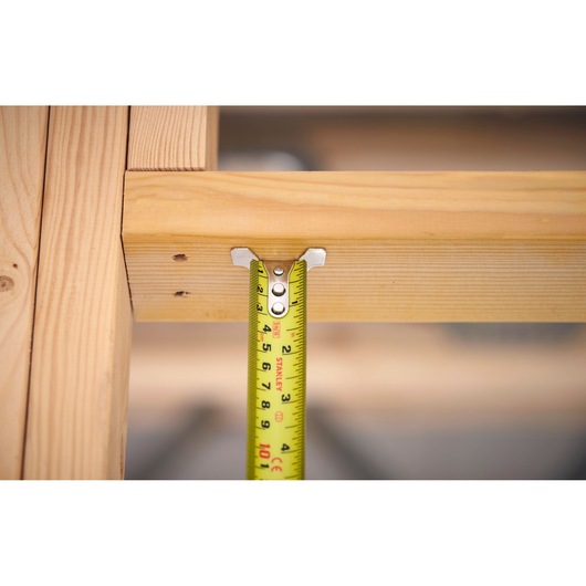 Stanley FMHT38215-5 tape measure measuring wooden frame, close-up, product photography.