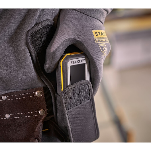 STANLEY FMHT77050-XJ laser distance measurer in black pouch, close-up view on work belt.