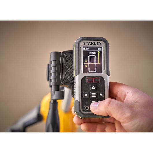STANLEY FMHT77050-XJ digital measuring device held in hand, close-up showing screen and buttons.