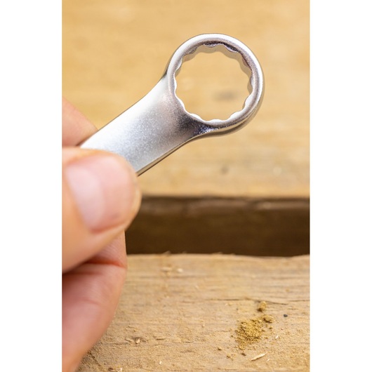 Photo of STANLEY FMMT82844-0 box-end wrench held near a wooden surface, close-up view.