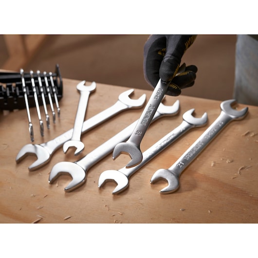 STANLEY FMMT82902-0 spanner set on workbench, one being held with glove, photography, oblique angle.
