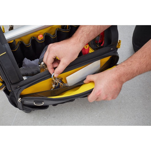 STANLEY FMST83296-1 tool bag top view with hands organizing keys and documents in yellow interior pocket.