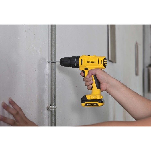 STANLEY SCH12S2 cordless drill being used to fasten a pipe to a wall, yellow and black design.
