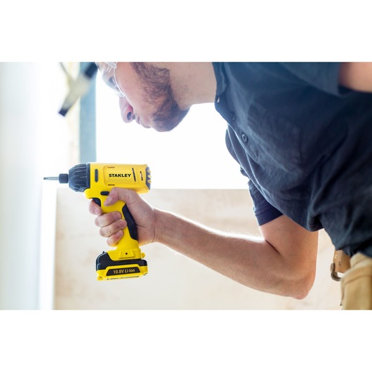 Photo of STANLEY SCI12S2 cordless drill in use, yellow and black, close-up side view.