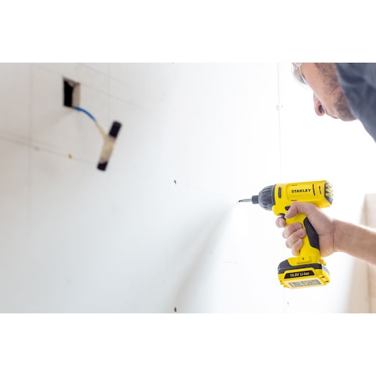 STANLEY SCI12S2 cordless drill being used on drywall, side angle view.