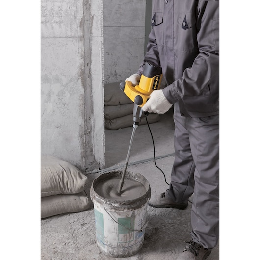 STANLEY SDR1400-KR electric mixer in use, mixing cement in a bucket on a construction site.