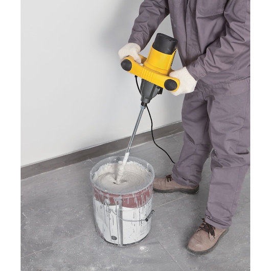 STANLEY SDR1400-KR mixer being used to blend paint in a metal bucket, close-up from above, indoor setting.