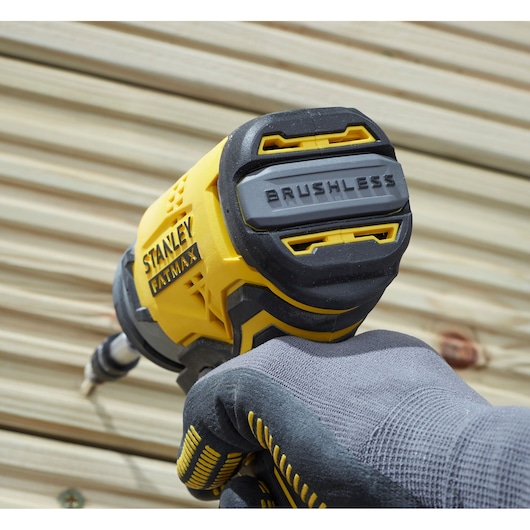 Photo of STANLEY SFMCF820B brushless impact driver held by gloved hand, close-up on back housing.