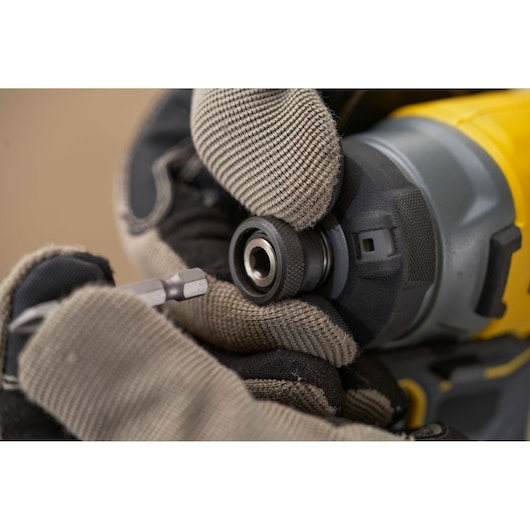 STANLEY SFMCF820B impact driver close-up, gloved hand inserting bit, yellow and black tool body visible.