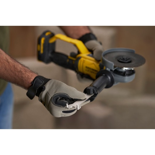STANLEY SFMCG400D1K angle grinder held by gloved hands, yellow and black body, close-up view.
