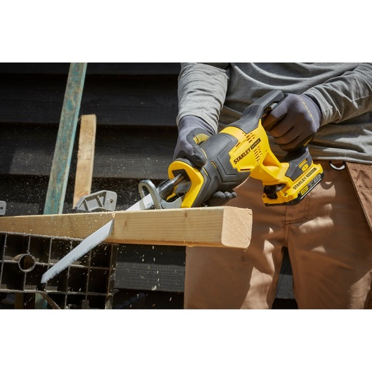 STANLEY SFMCS300D1K cordless reciprocating saw cutting wood, close-up outdoor photography.