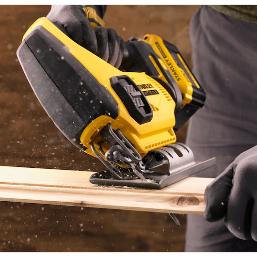 STANLEY SFMCS600D1K cordless jigsaw cutting wood, close-up with sawdust flying.