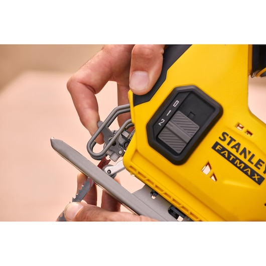 Photo of STANLEY SFMCS600D1K jigsaw, yellow body, close-up view of blade insertion and control switch.