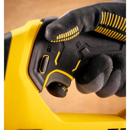 Close-up photo of STANLEY SFMCS600D1K photography tool handle with textured black and yellow grip, glove holding trigger.
