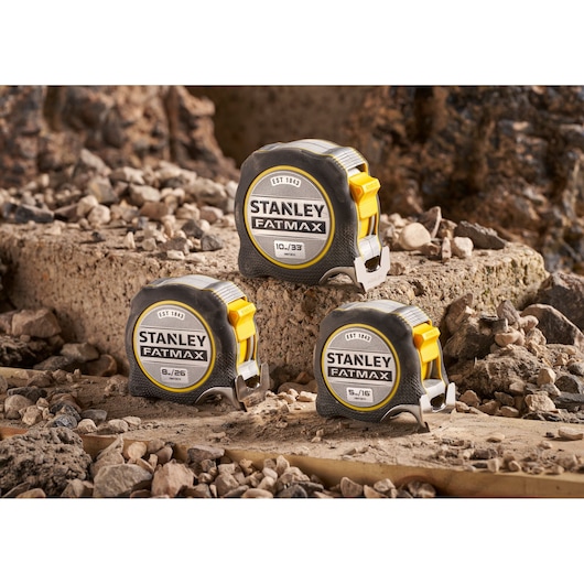 Stanley FMHT38233-5 Fatmax tape measures on rocky construction site, showing three tape sizes.