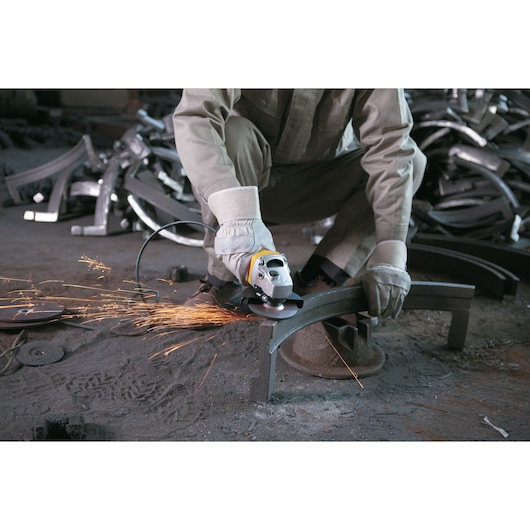 STANLEY SGS1045 angle grinder in use, cutting metal, producing sparks, industrial workshop setting.
