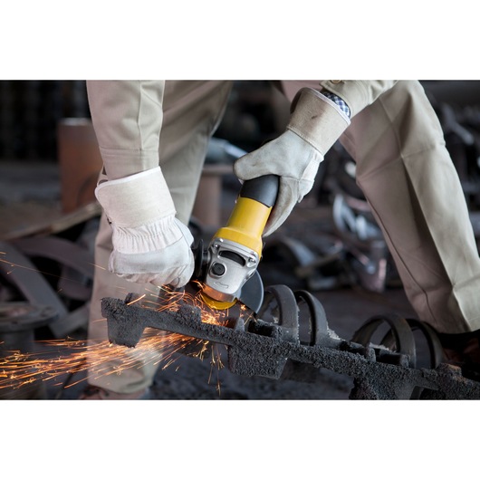 STANLEY SGV115 angle grinder in use, producing sparks while cutting metal, close-up action shot.