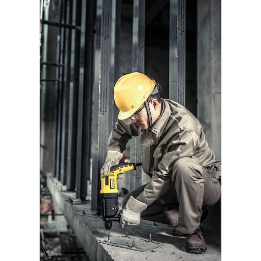 Photo of STANLEY SHR263KC rotary hammer drill used by worker in safety gear drilling into concrete.