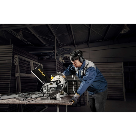 Photo of STANLEY SM16-B3 miter saw in use by worker in industrial workshop.