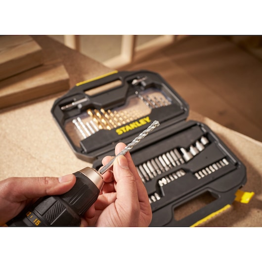 STANLEY STA7184 drill bit set with open case and hand inserting bit into drill, photographed close-up.