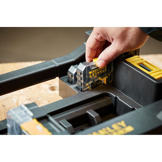 STANLEY STA88580 digital measuring tool held in hand, shown inserted in black and yellow storage case, close-up.