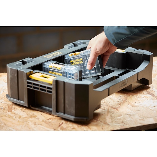 STANLEY STA88580 organizer tray with removable clear plastic cases, shown on a workbench, hand taking one case.