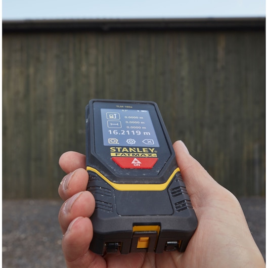 Photo of a STANLEY STHT1-77139 laser distance measurer held in hand, screen displaying measurement in meters.