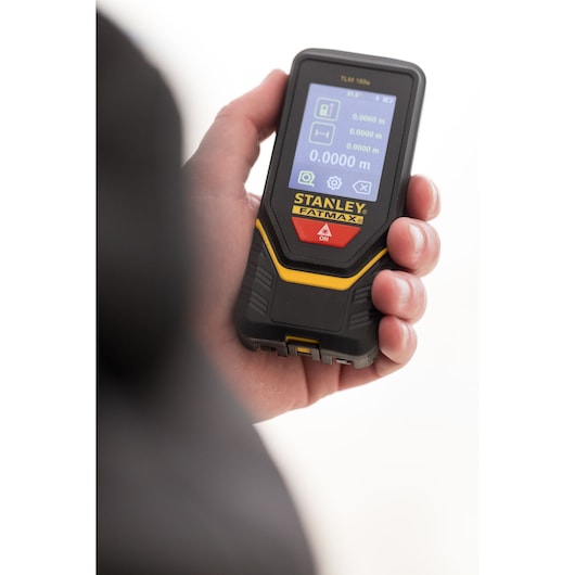 Photo of STANLEY STHT1-77139 FATMAX laser distance measurer held in hand, front display screen visible.